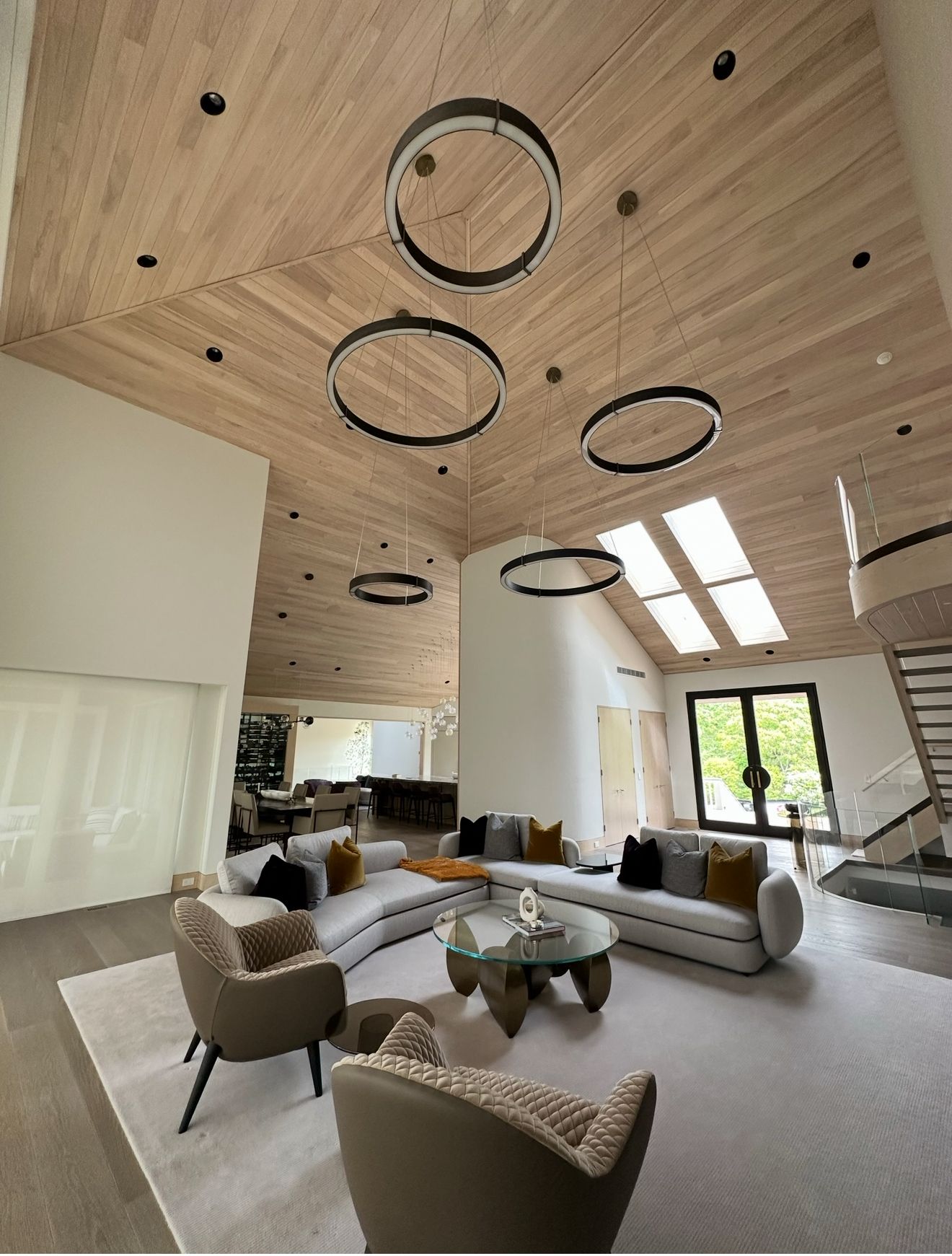 Spacious living room with wood-paneled ceiling, modern circular light fixtures, and curved sofas.