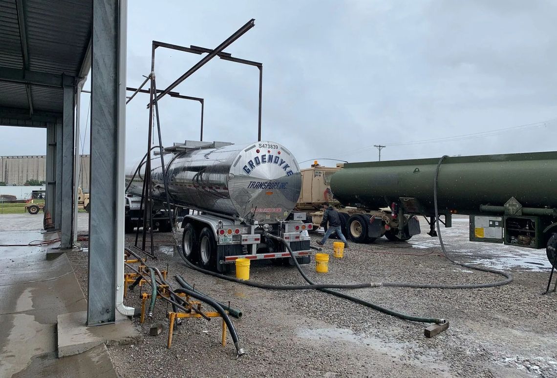 A tanker truck is being filled with gas at a gas station.