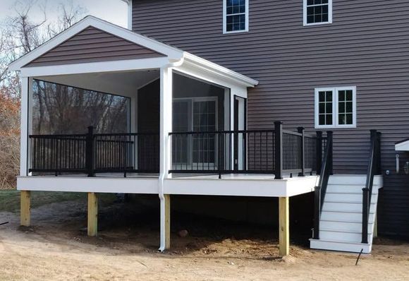 Porch with black railings and stairs on a house exterior.