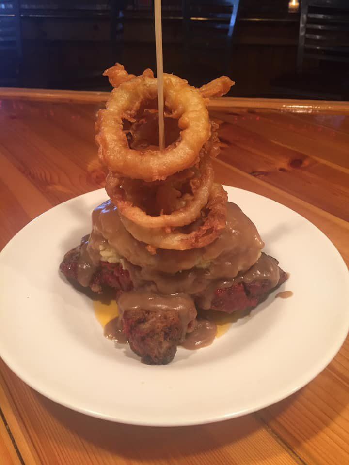 Delicious food with onion rings on top