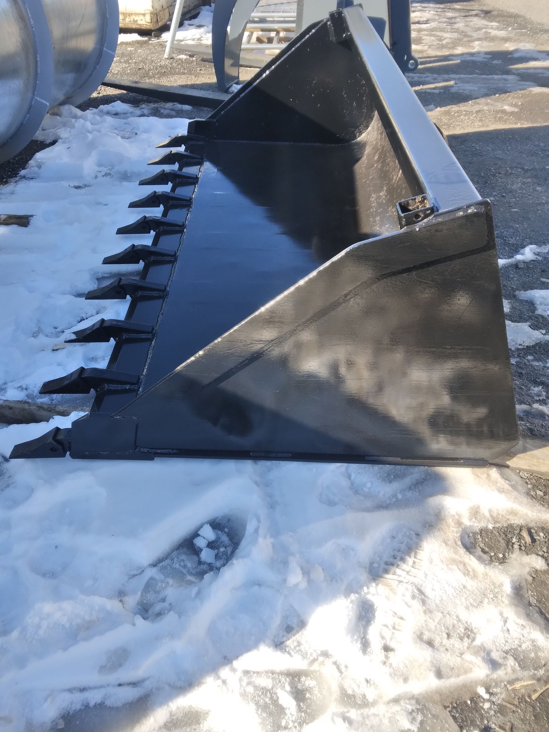 A black bucket is sitting on top of a pile of snow.