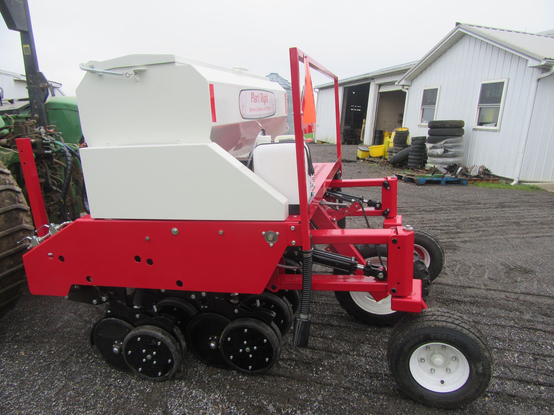 A red and white tractor is parked in front of a white building