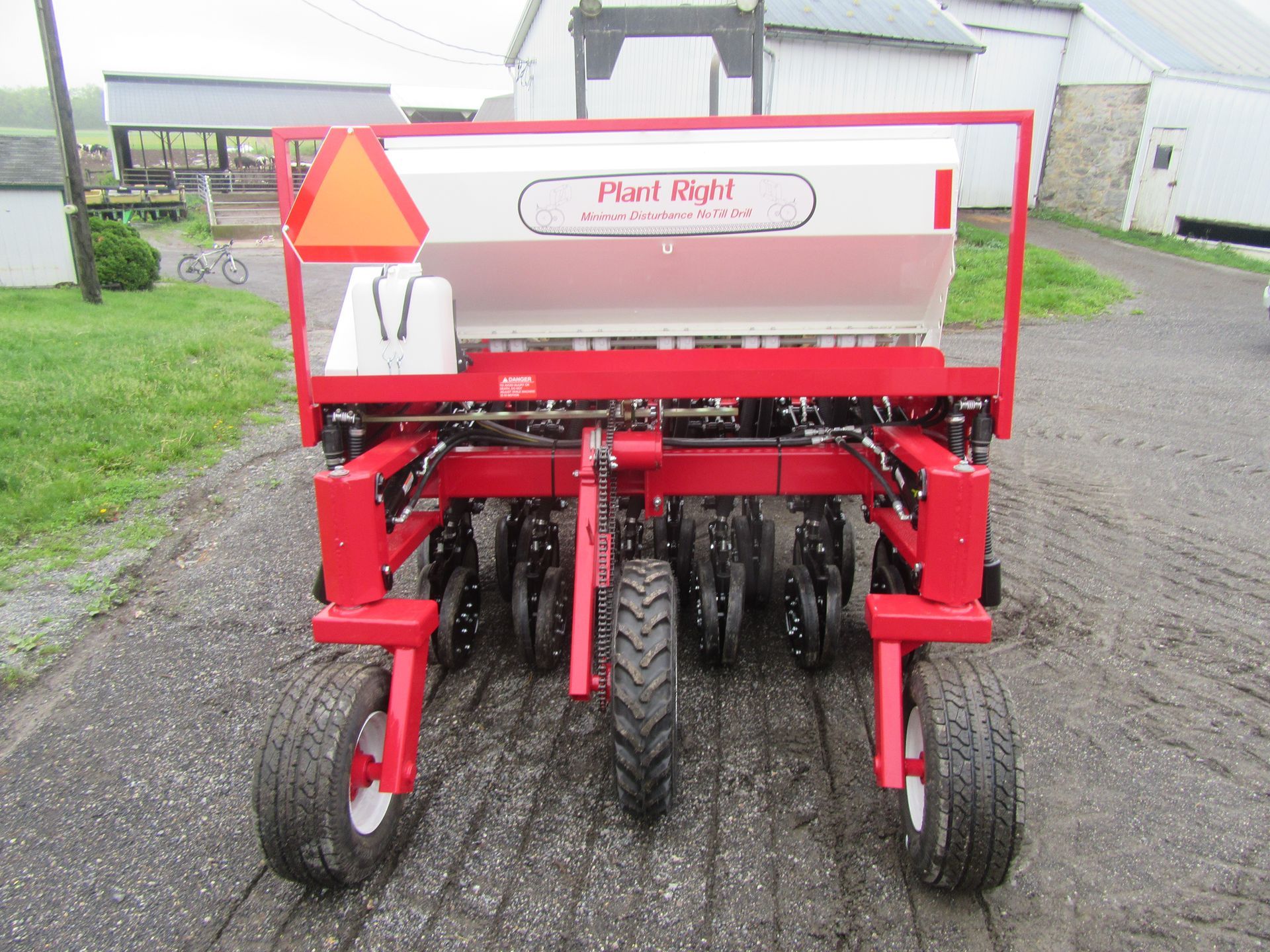 A red and white pearl root planter is parked on a dirt road