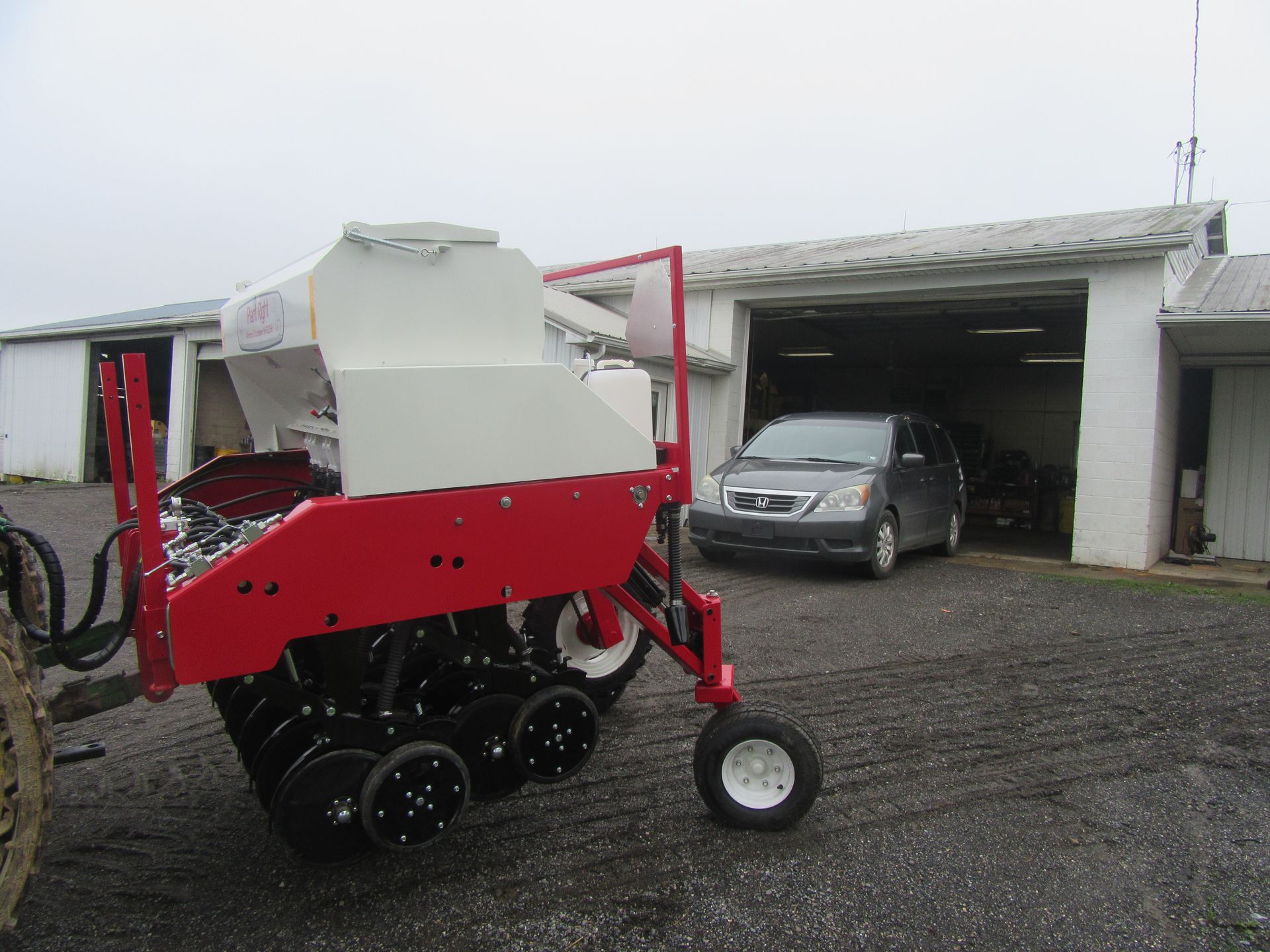 A red and white tractor is parked in front of a garage.