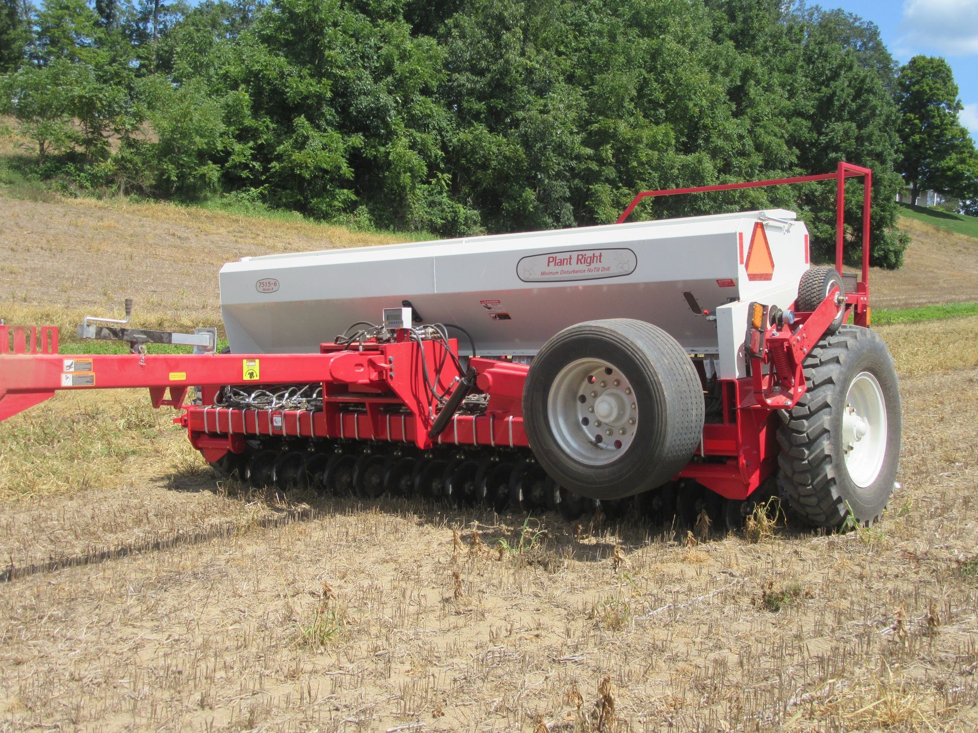 A red and white tractor is parked in a field