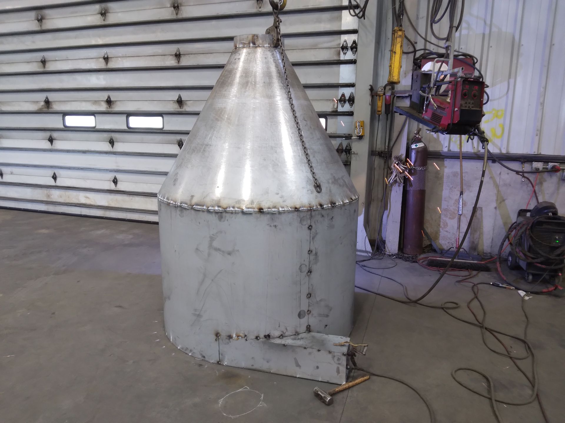 A large metal cone is being welded in a garage