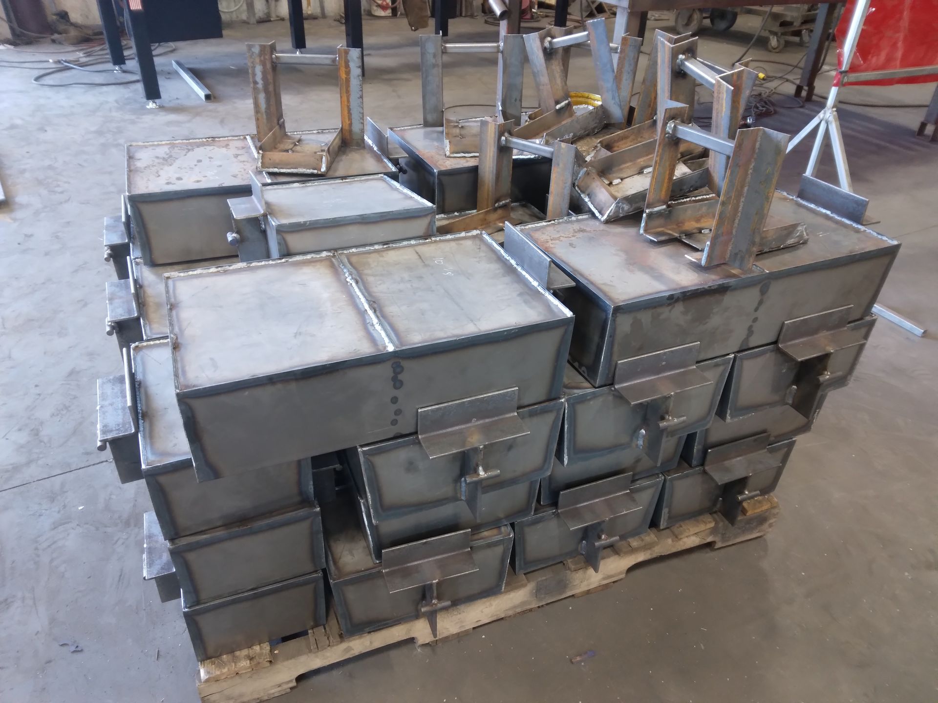 A pile of metal boxes stacked on top of each other on a wooden pallet.