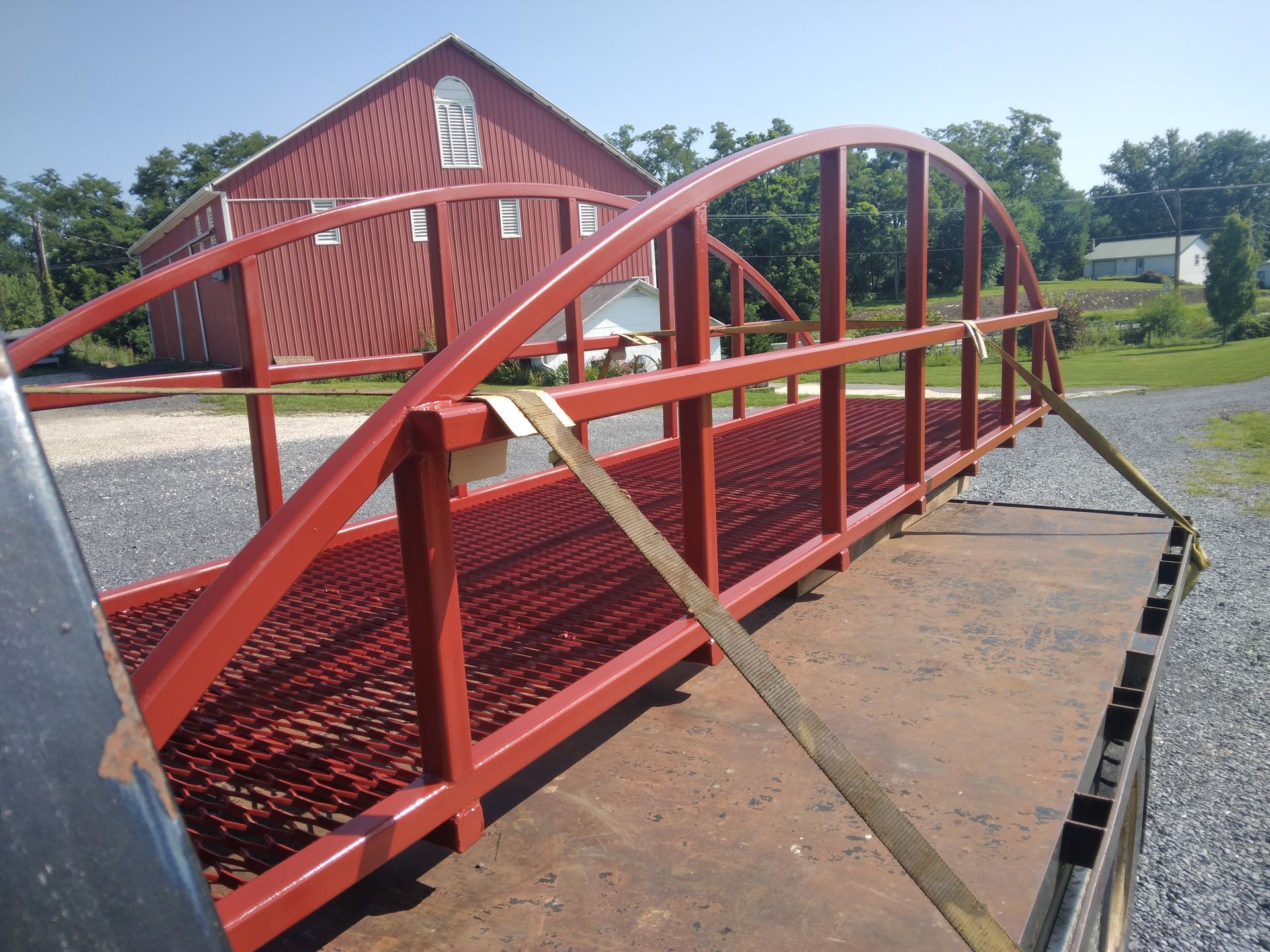 A red bridge is being built in front of a red barn