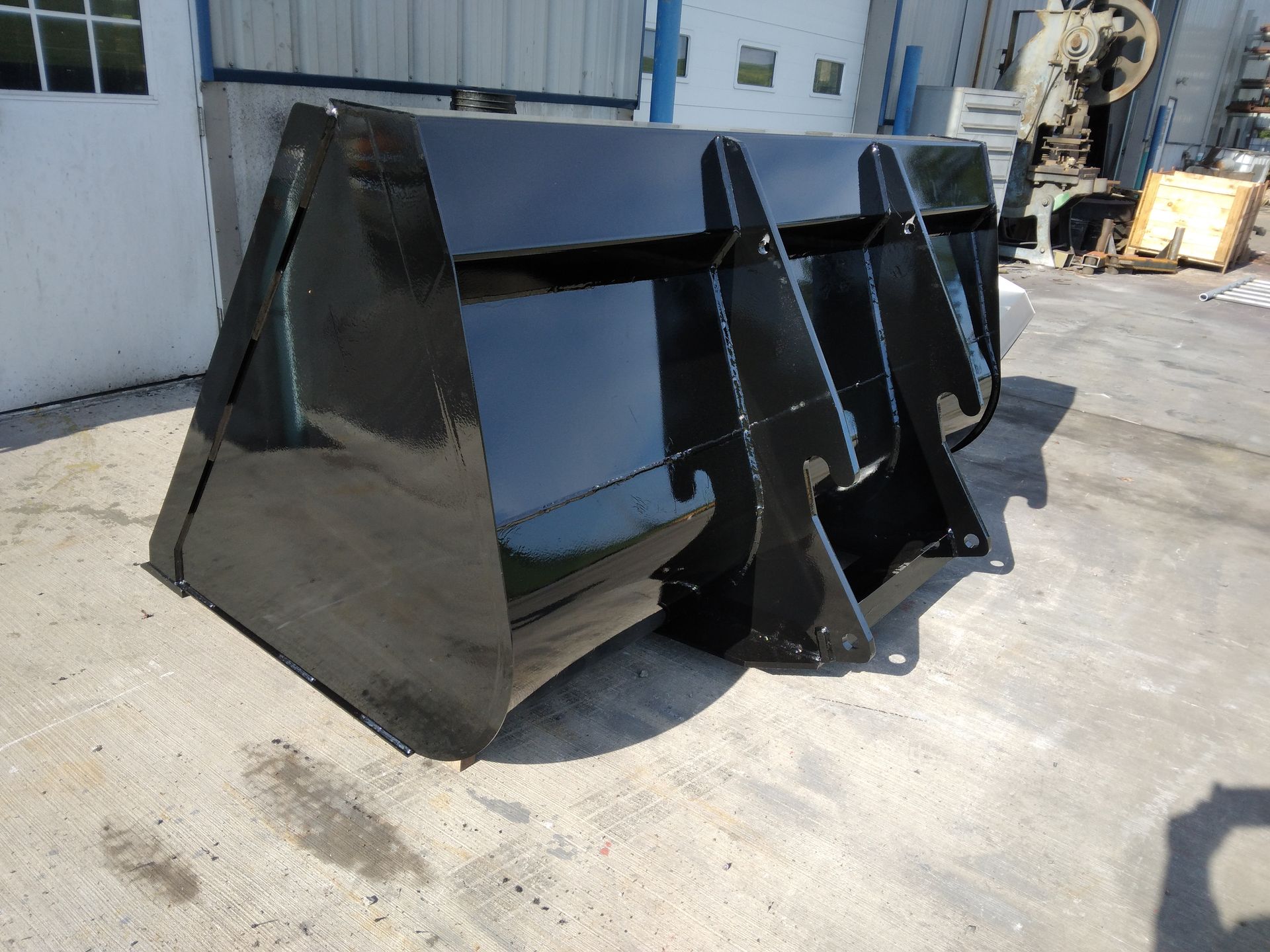 A black bucket is sitting on the ground in front of a building