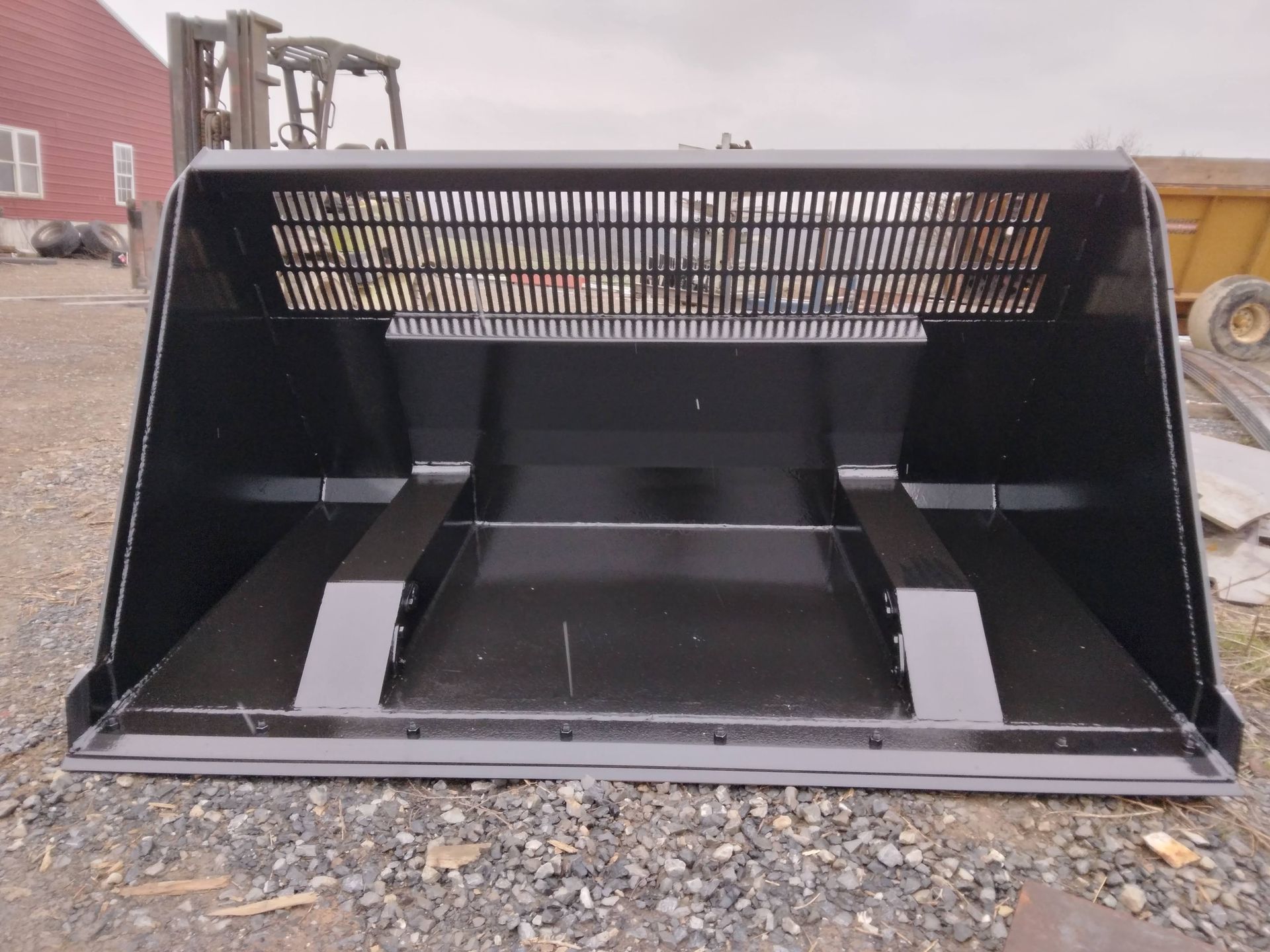 A black bucket is sitting on top of a gravel field.
