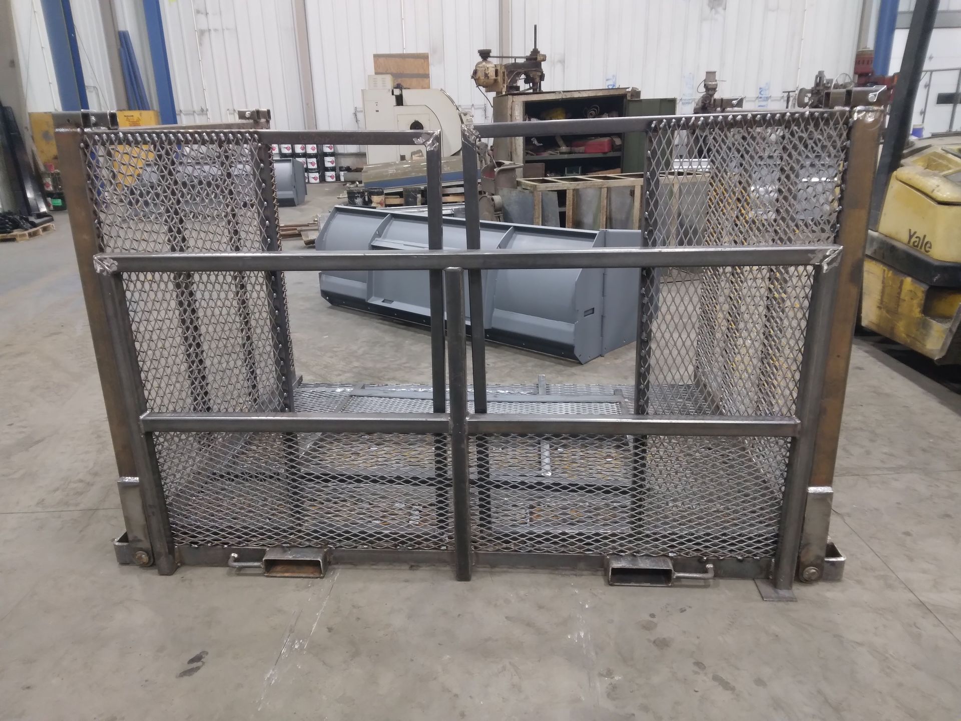 A metal fence with a yellow forklift in the background