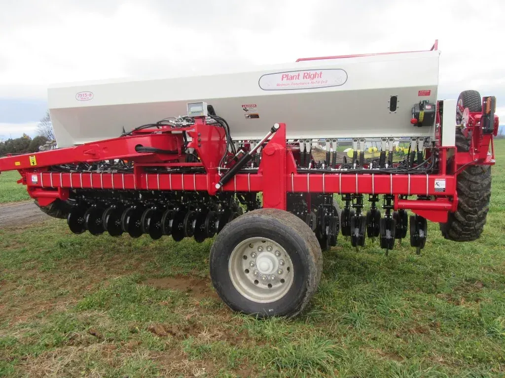 A red and white tractor is parked in a grassy field