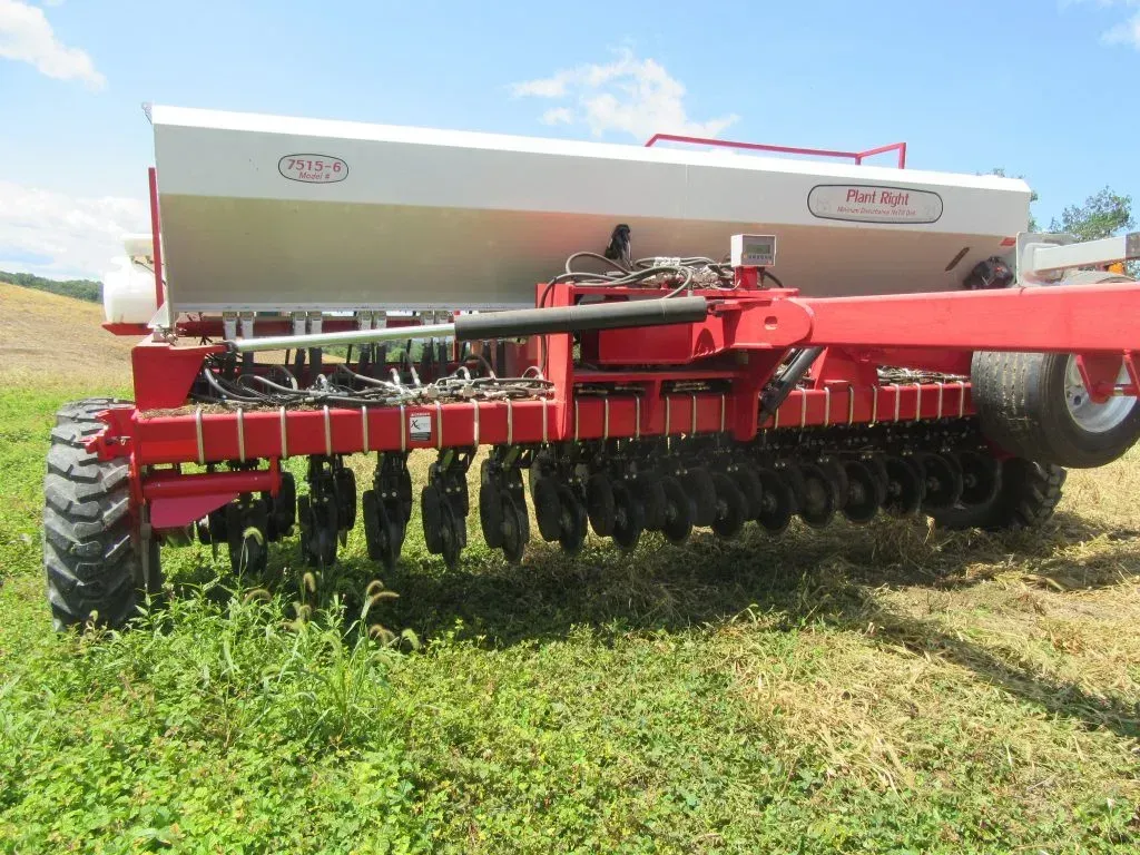 A red and white tractor is parked in a grassy field.