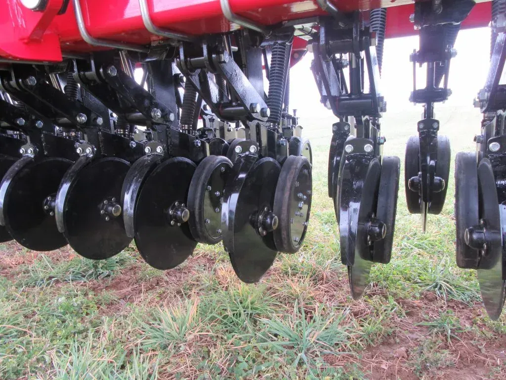 A red and black tractor is sitting in a grassy field