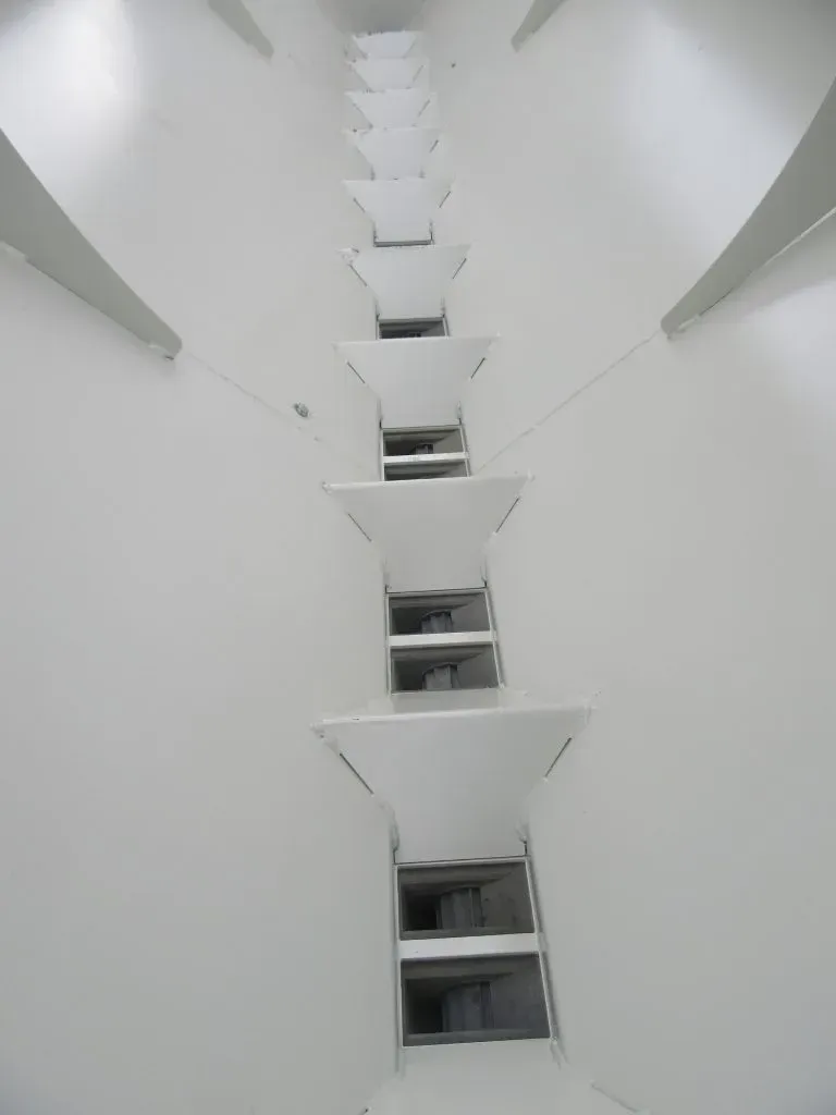 A row of white stairs going up a white wall.