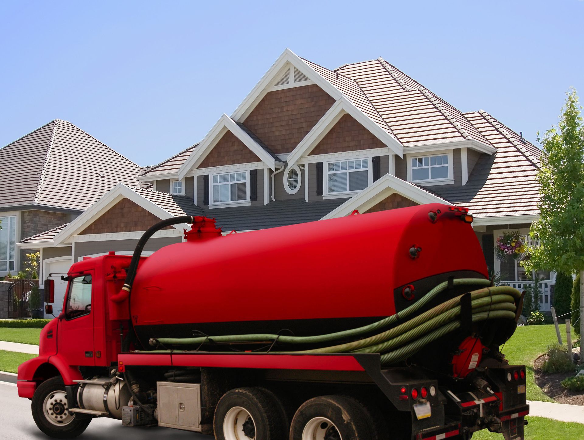 Red septic truck parked in front of a house.