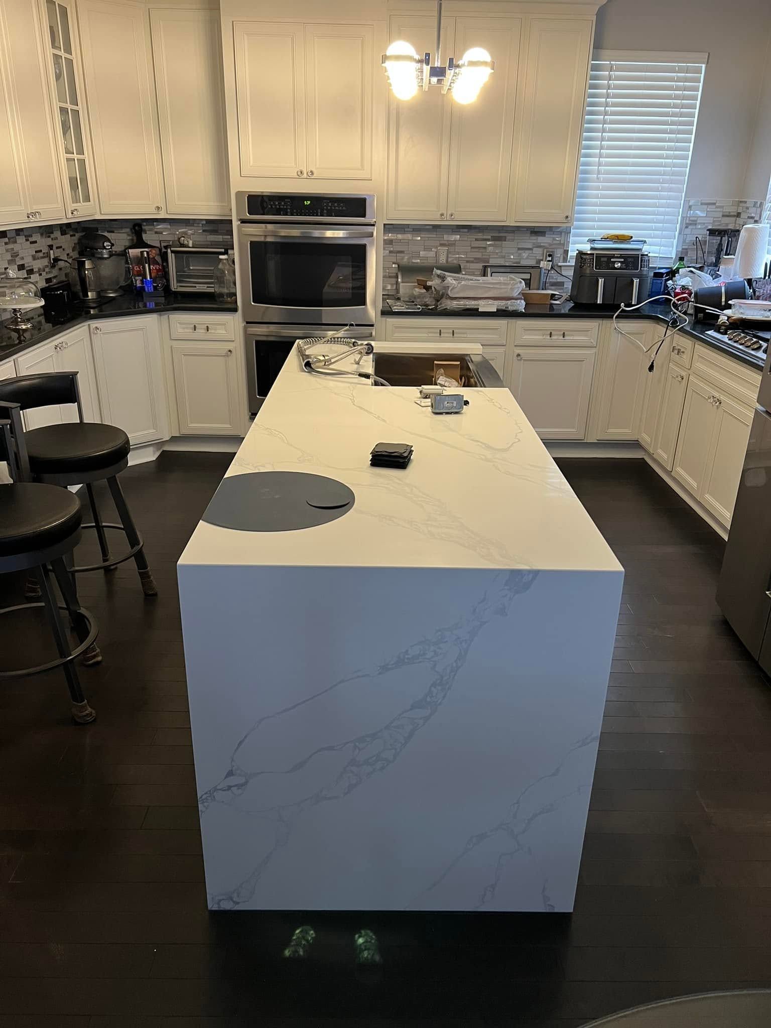A kitchen with a large white island in the middle of it.