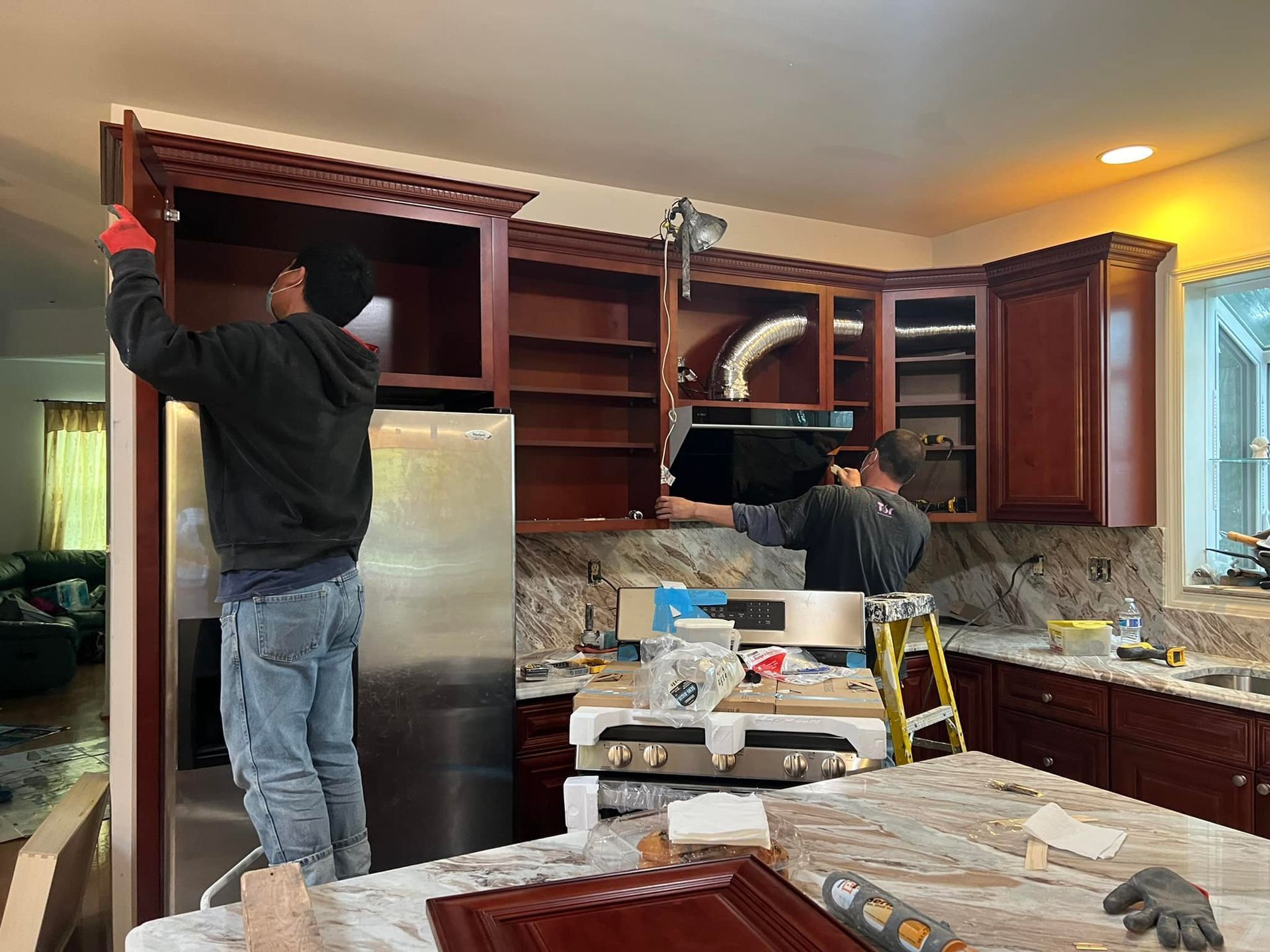 Two men are working on a kitchen in a house.