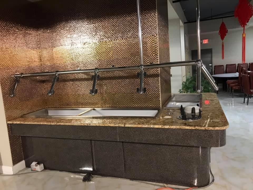 A buffet line in a restaurant with a copper wall behind it.