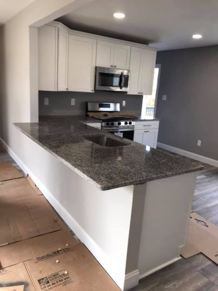 A kitchen with granite counter tops and white cabinets
