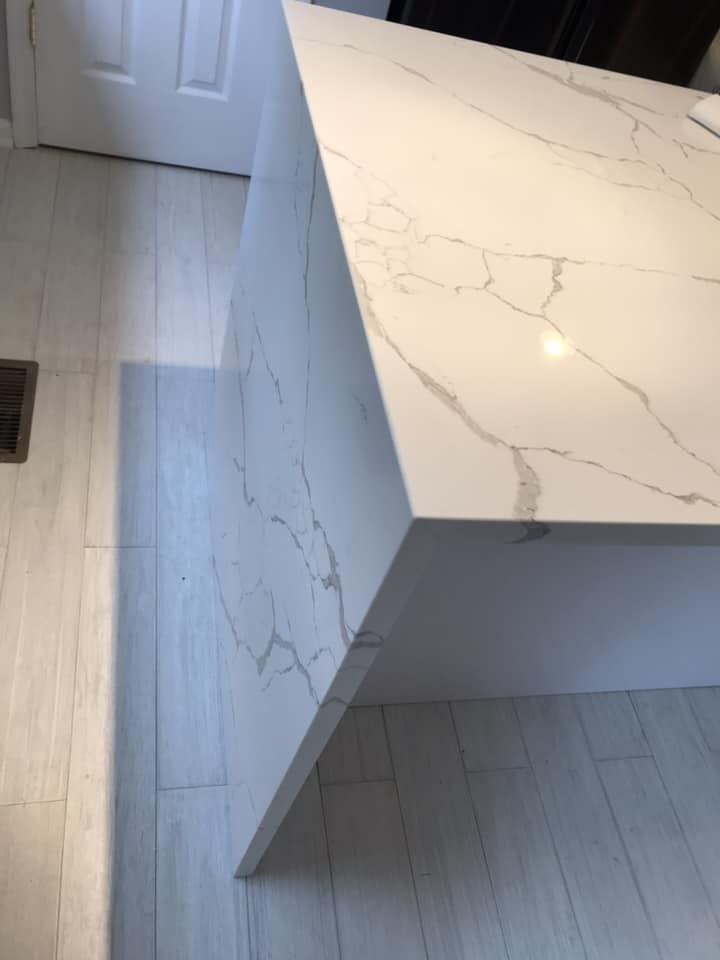 A white marble counter top in a kitchen with a wooden floor.