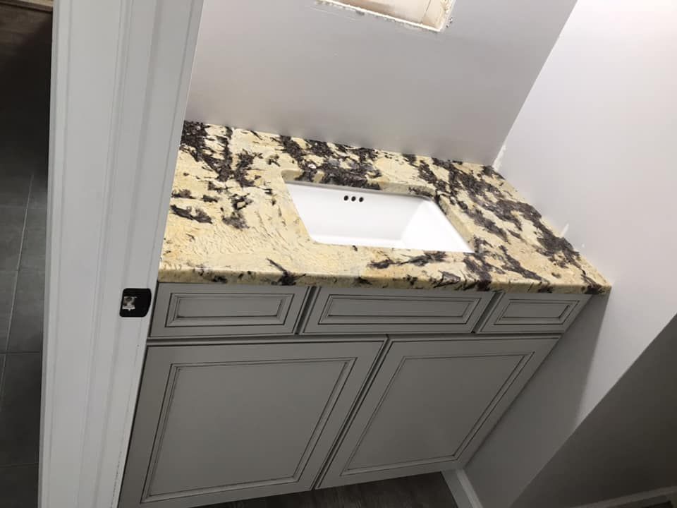 A bathroom vanity with a sink and granite counter top.