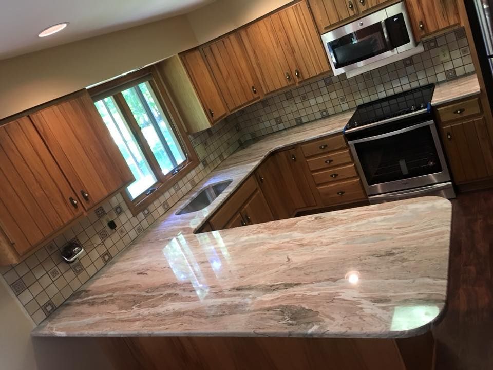 A kitchen with wooden cabinets , granite counter tops , stainless steel appliances and a large island.