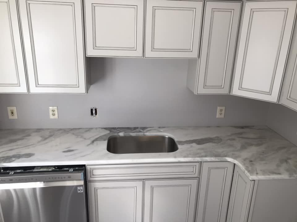 A kitchen with white cabinets and a stainless steel dishwasher