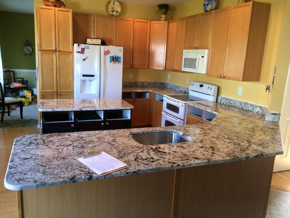 A kitchen with granite counter tops , stainless steel appliances , and wooden cabinets.
