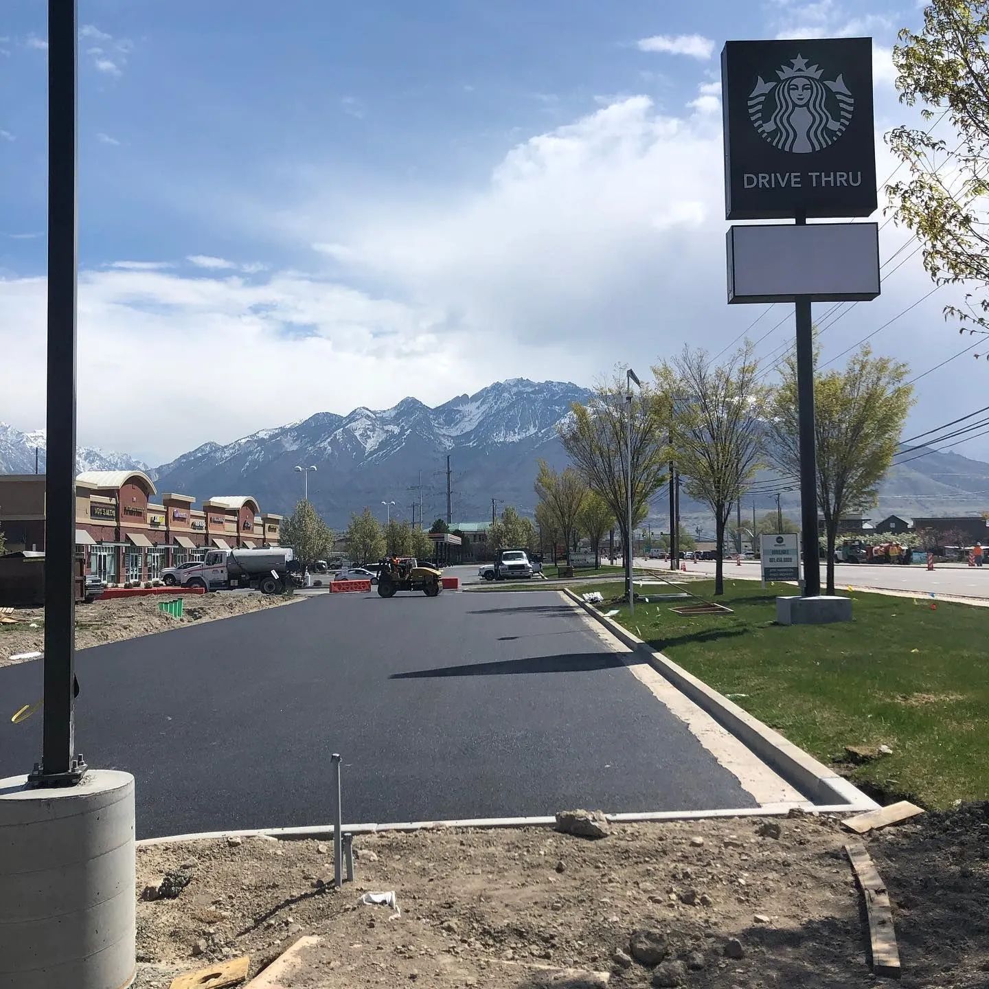 New black asphalt drive-thru lane at Starbucks under construction, with mountain backdrop.