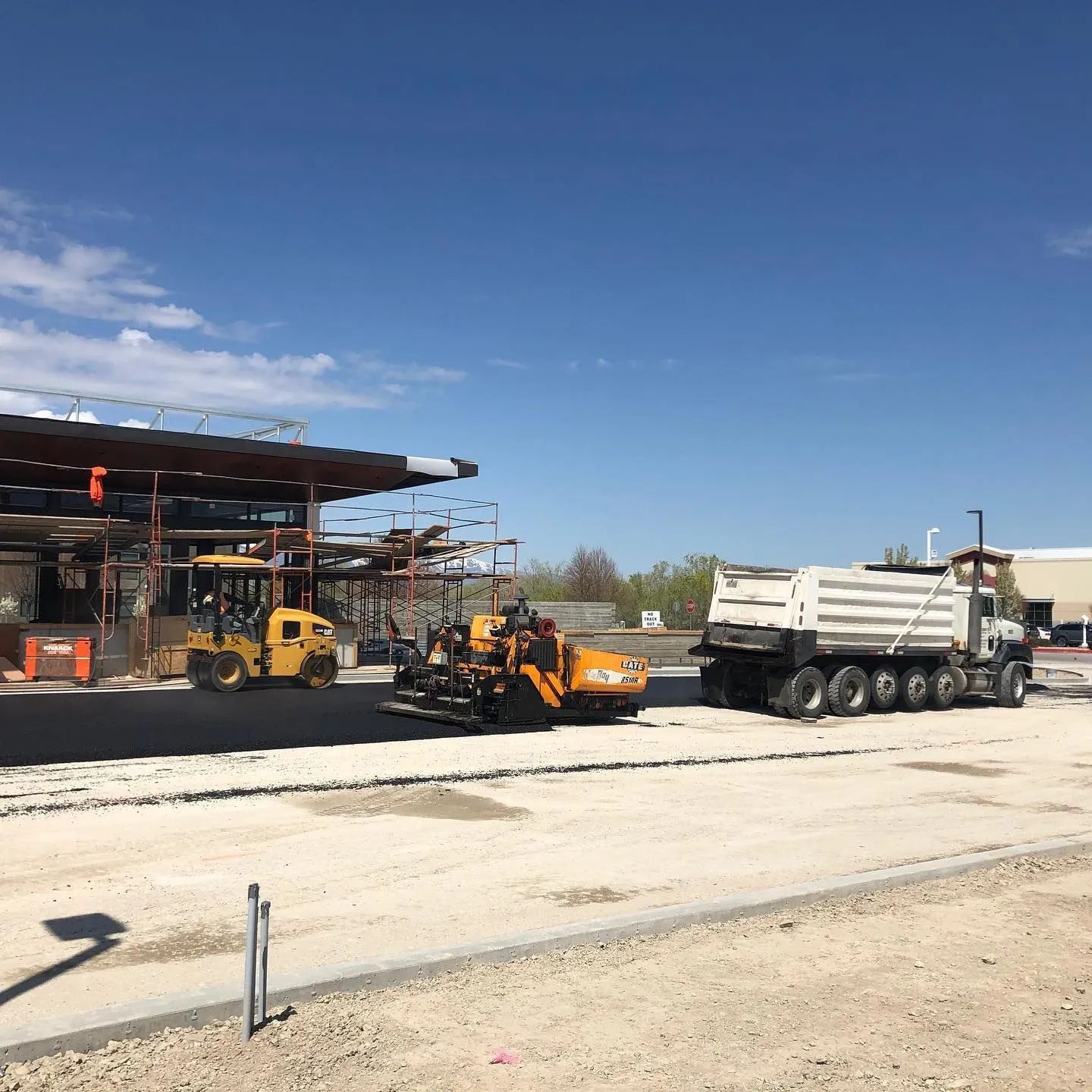Road paving construction site with machines and truck.