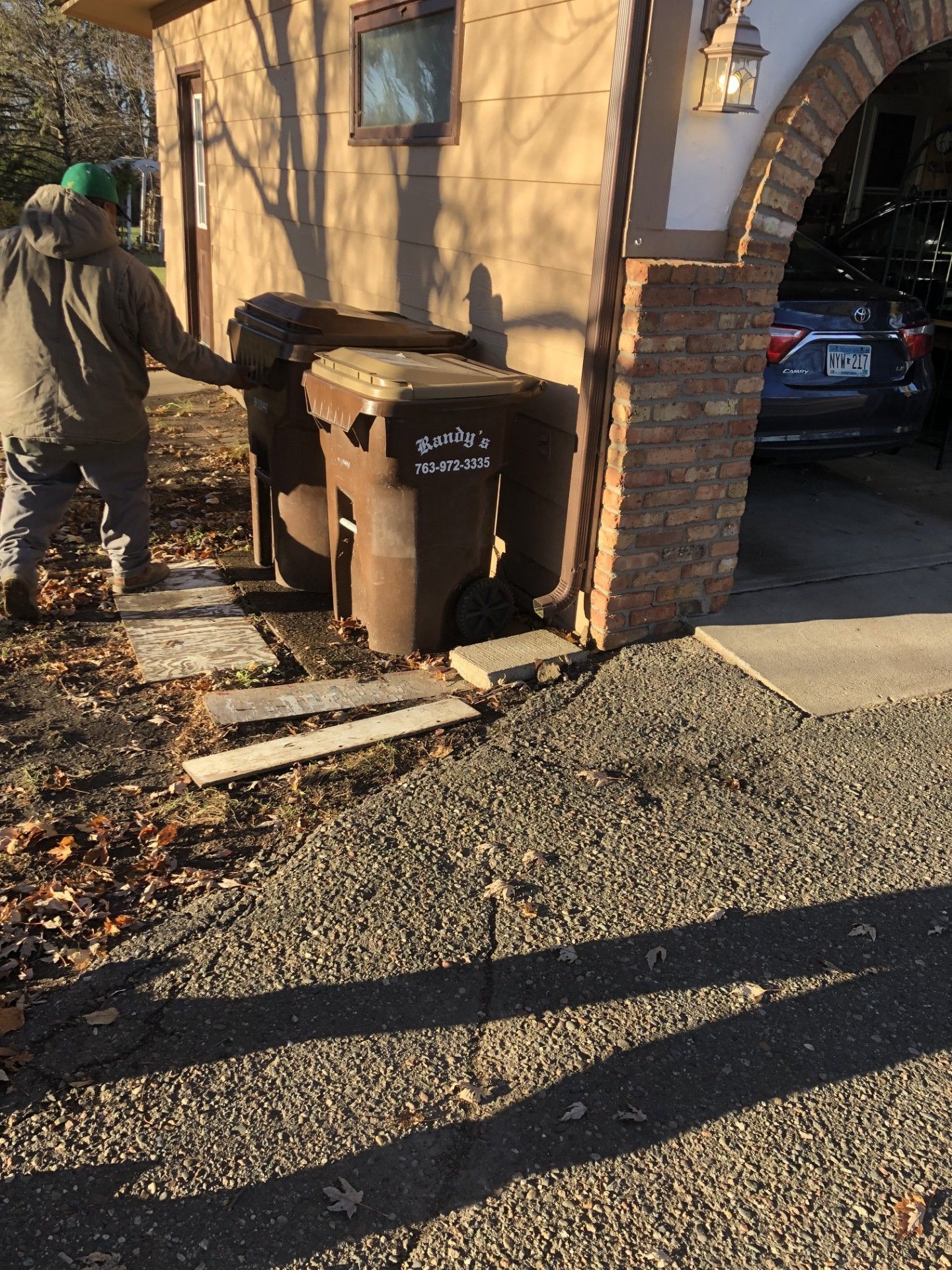 A man is pushing a garbage can into a garage.