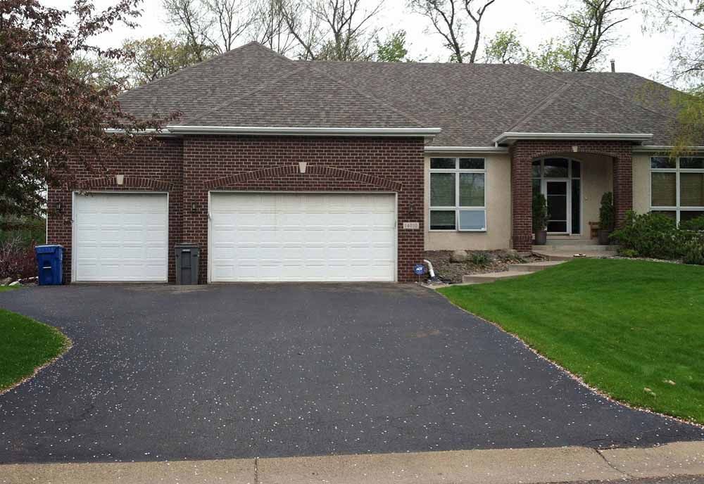 a brick house with two garage doors and a driveway