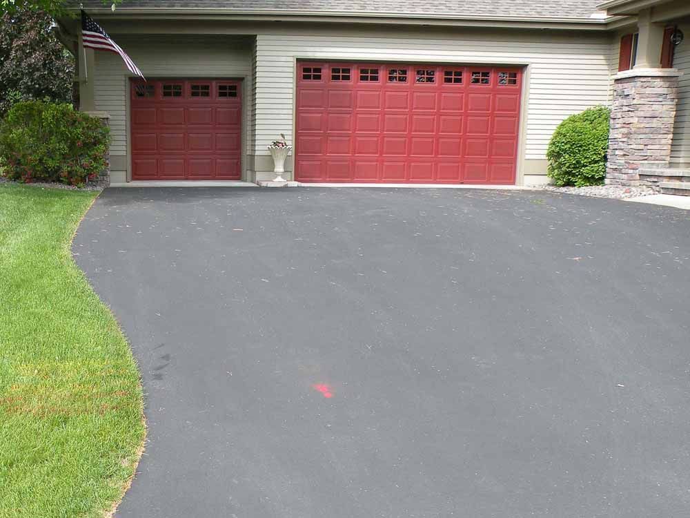 a driveway leading to a house with two red garage doors
