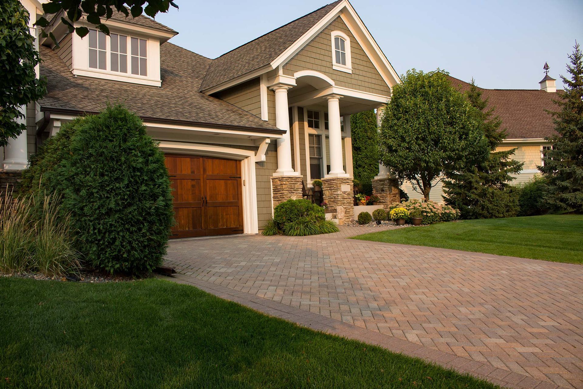 a large house with a wooden garage door and a brick driveway