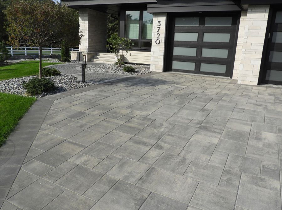 A modern driveway in front of a house with a black garage door