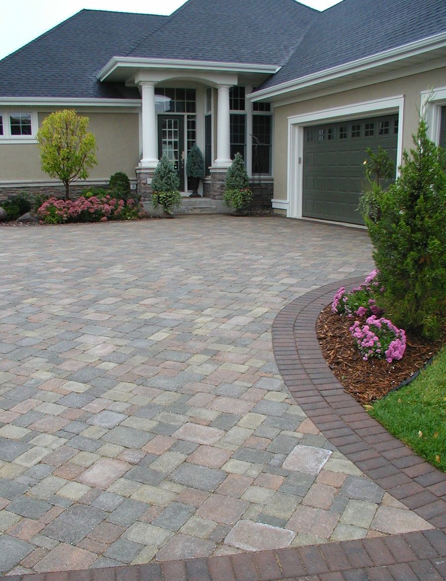 A large house with a brick driveway in front of it