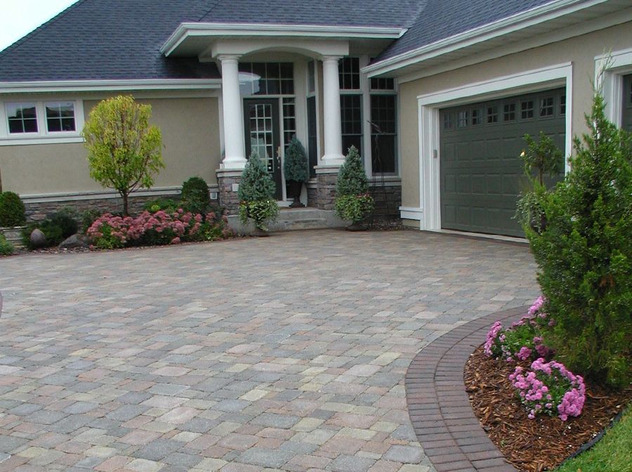 A large elegant house with a brick driveway and a garage