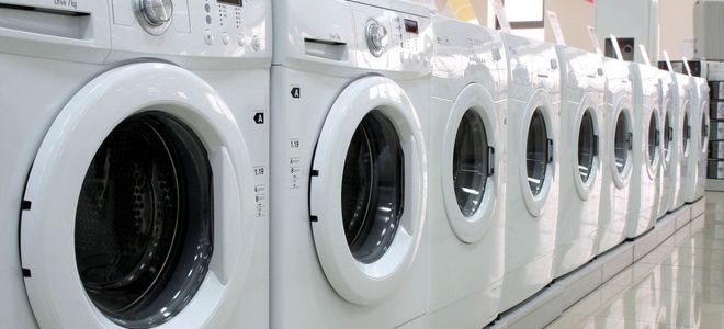 Row of white washing machines in a laundromat.