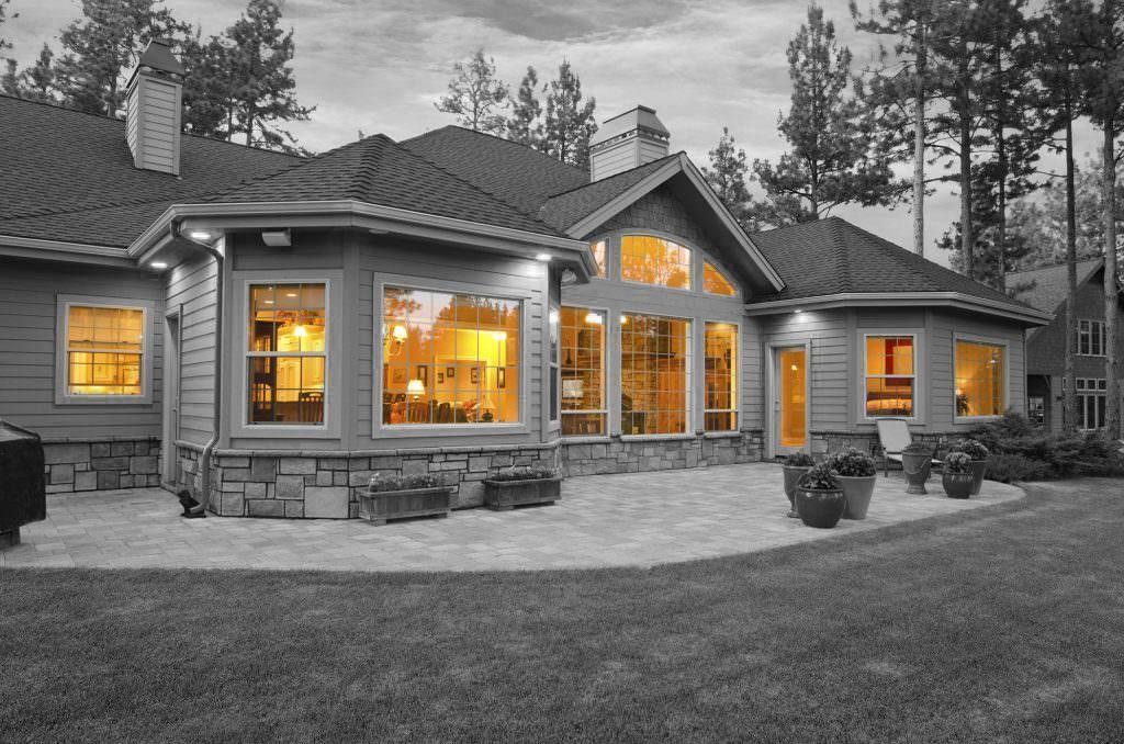 A house at dusk with lit windows, black and white except for the glowing interiors.