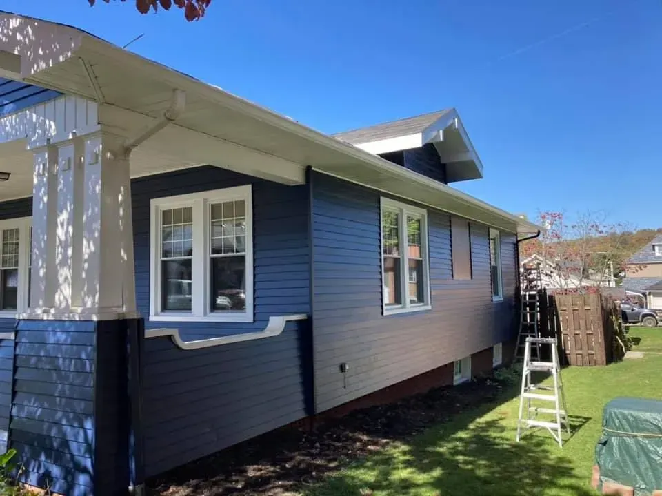 A blue and white house with a ladder in front of it.