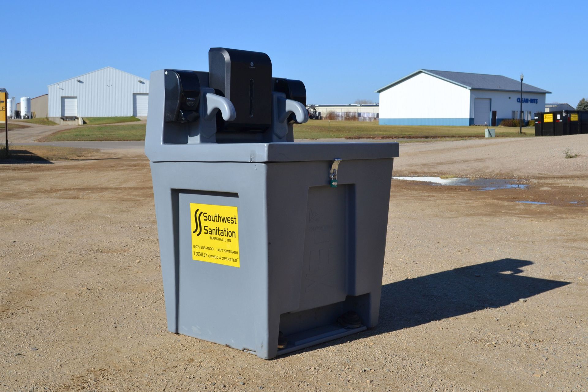 Gray portable handwashing station with soap and paper towel dispensers, outdoors.