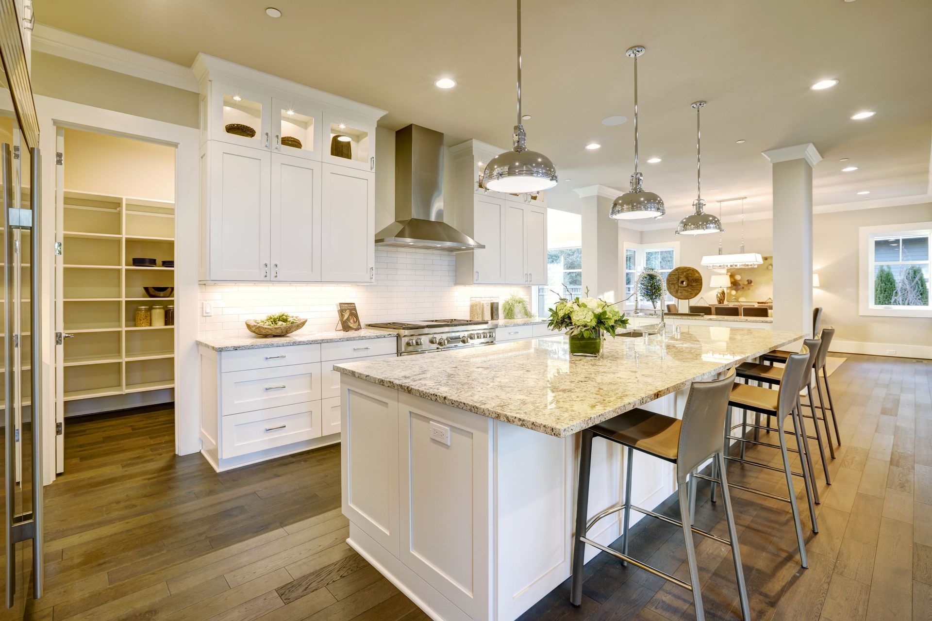 A kitchen with white cabinet , granite counter tops, stainless steel appliances and a large island.