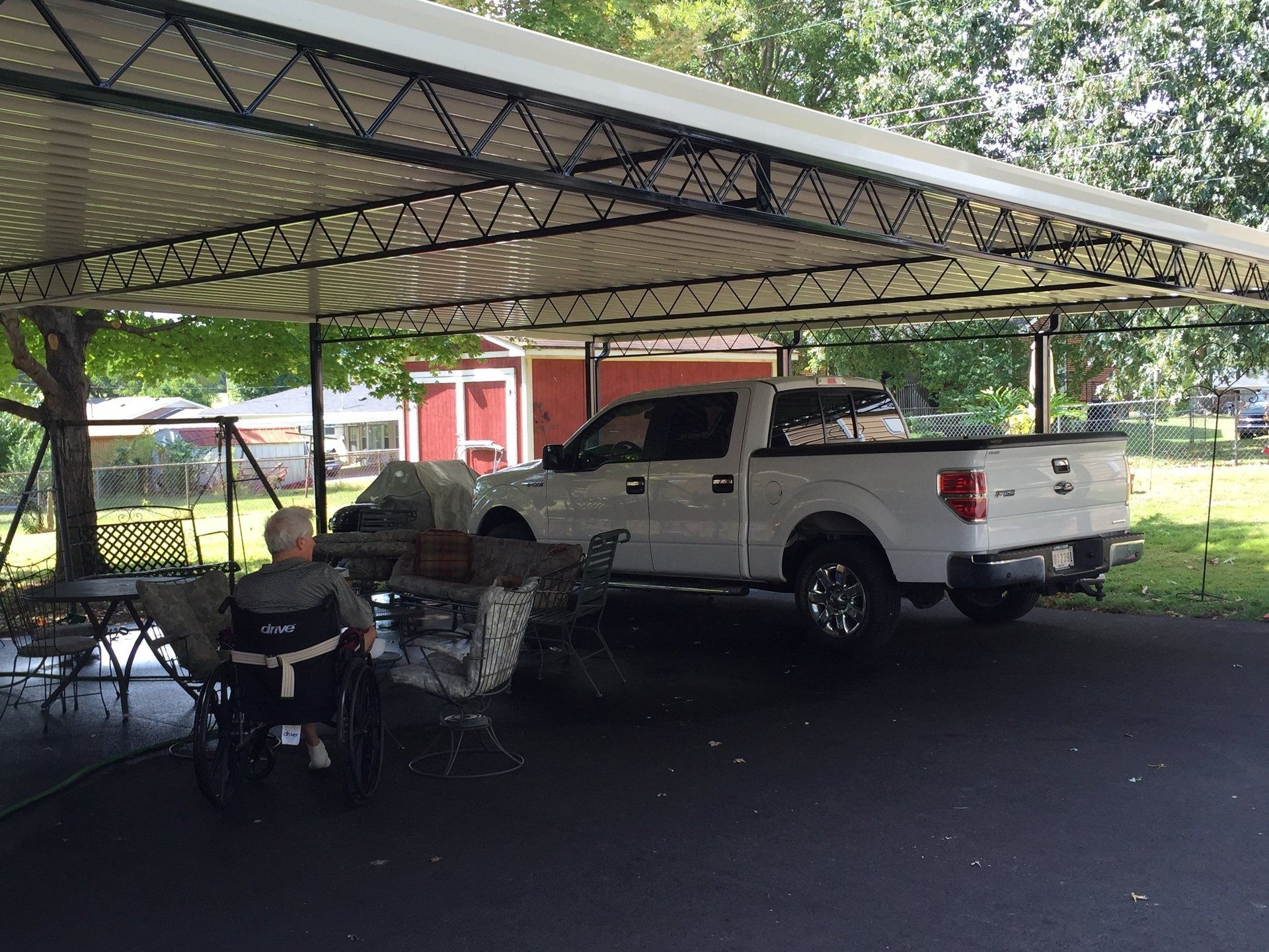 A white truck is parked under a canopy in a parking lot.