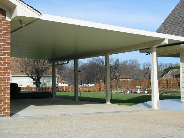A white carport with a brick building in the background