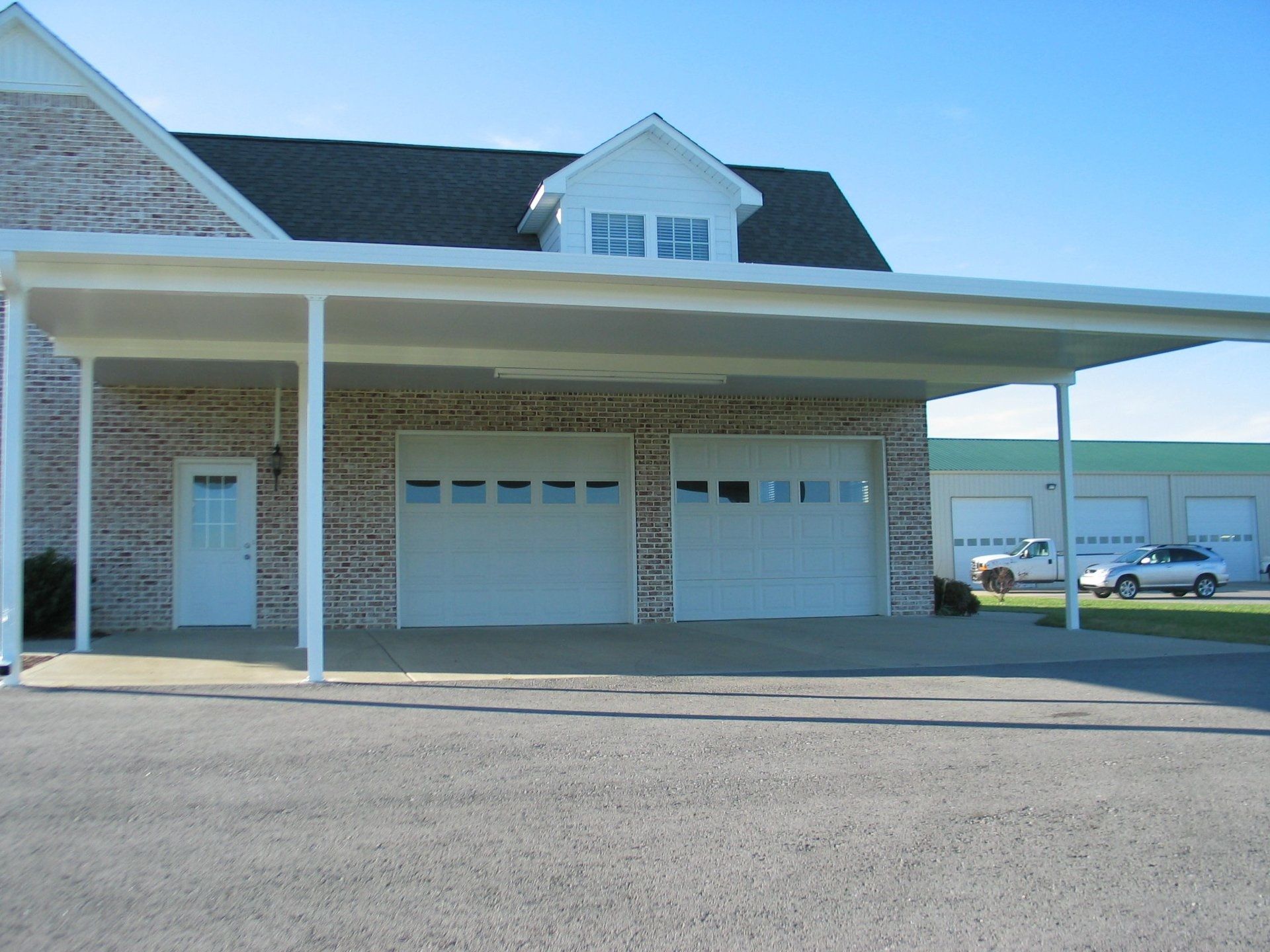 A brick house with a white garage door and a carport