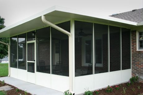 A screened in porch on the side of a brick house.