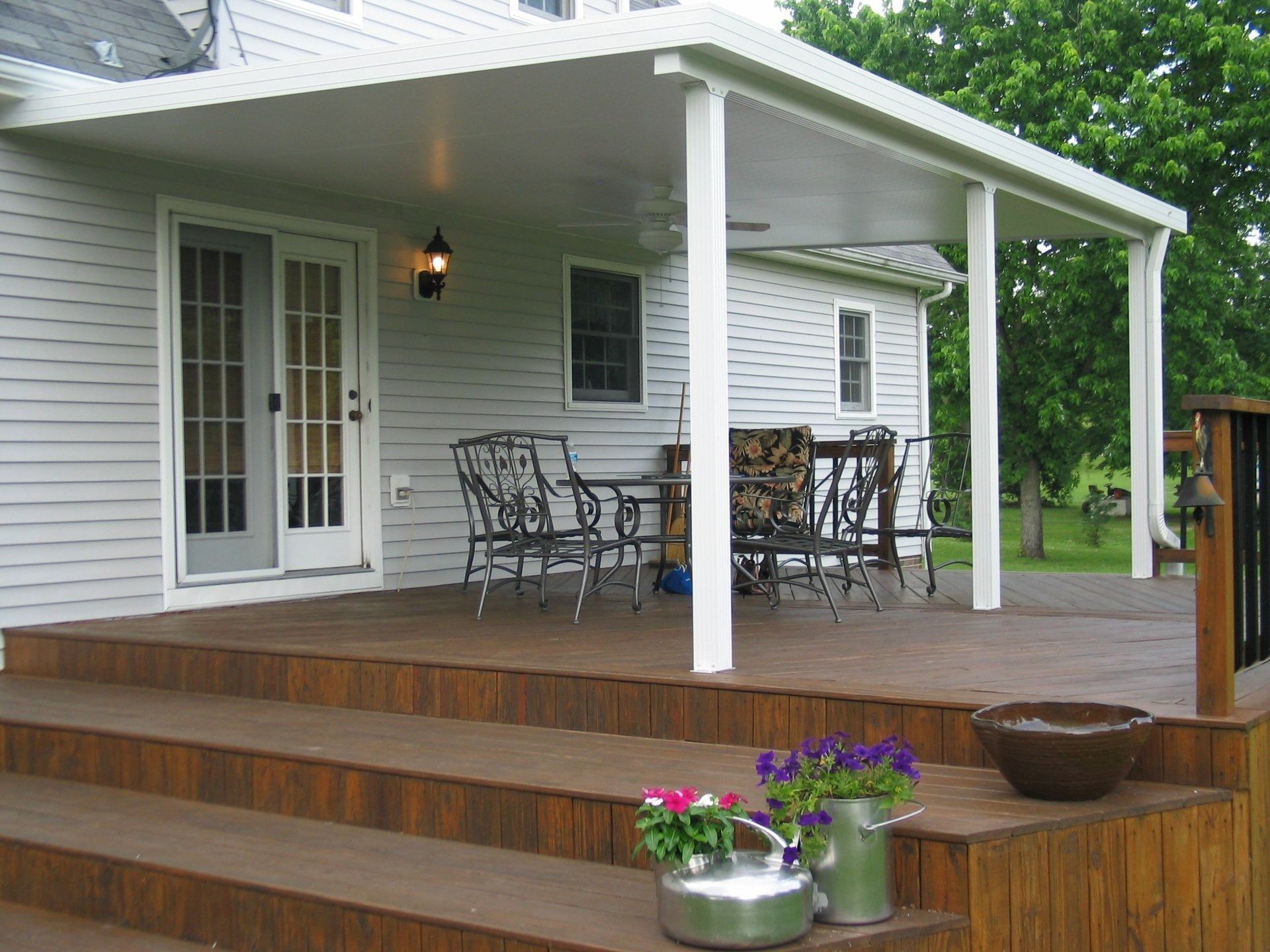 A white house with a covered porch with chairs and a table
