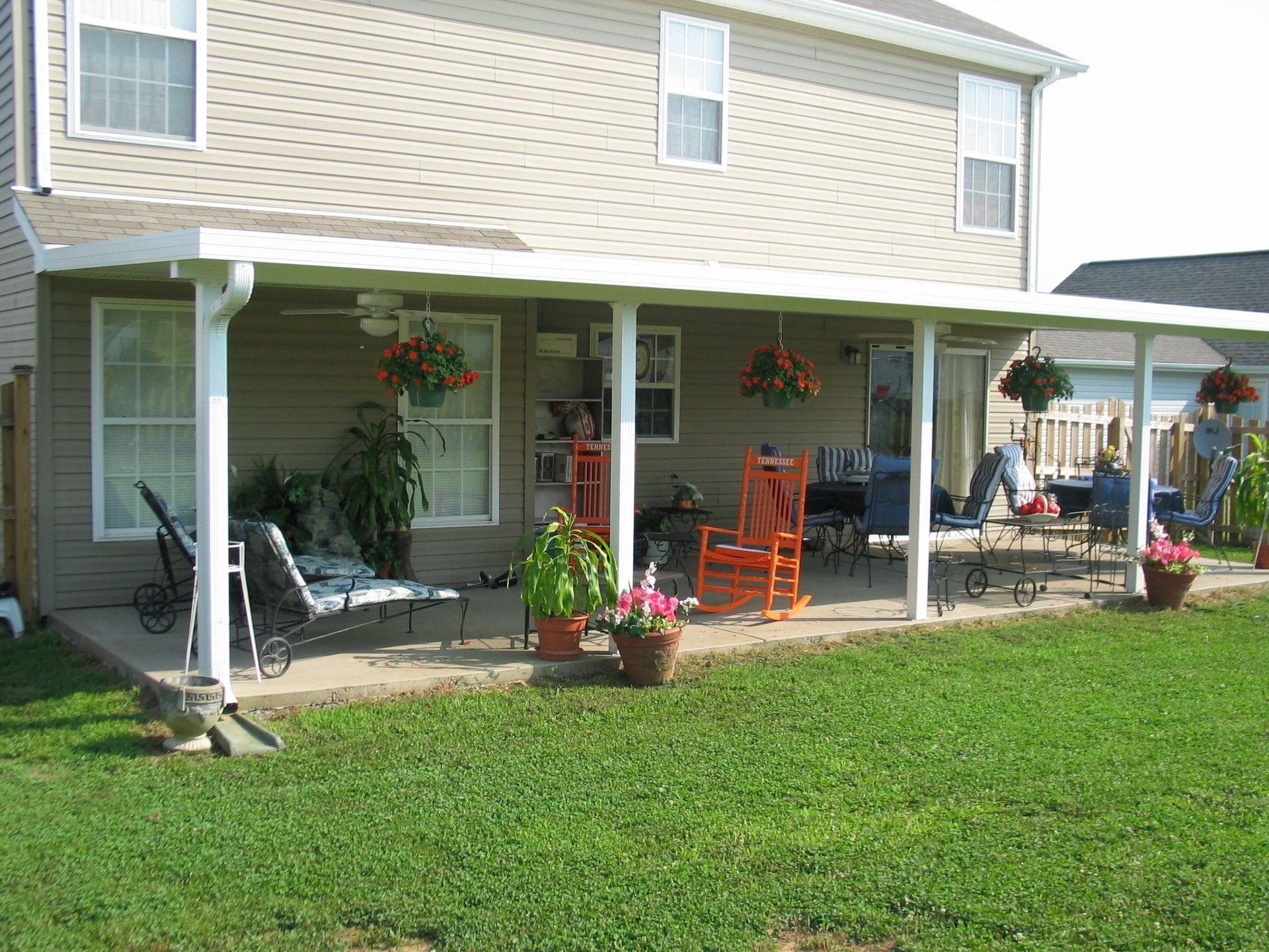 A house with a covered patio with rocking chairs and a table.