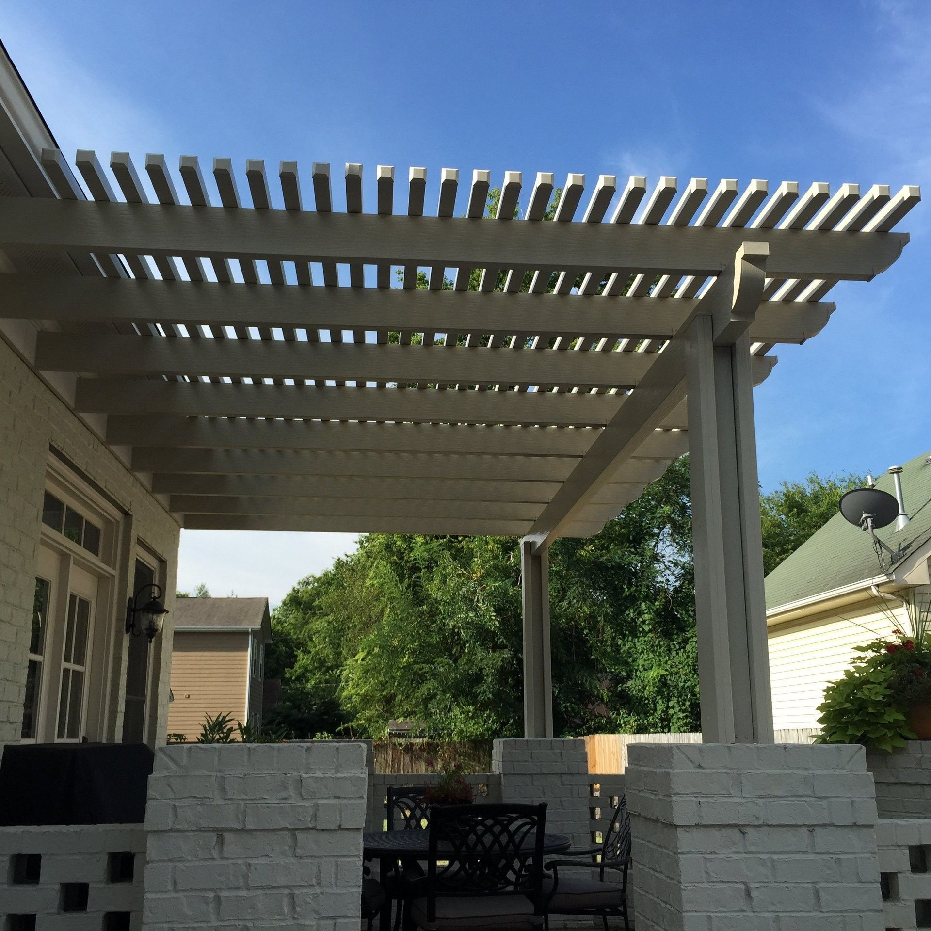 A white pergola with a blue sky in the background